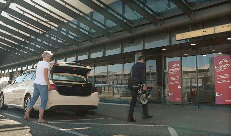 Kwiggle-Faltrad vom Taxi in den Flughafen tragen